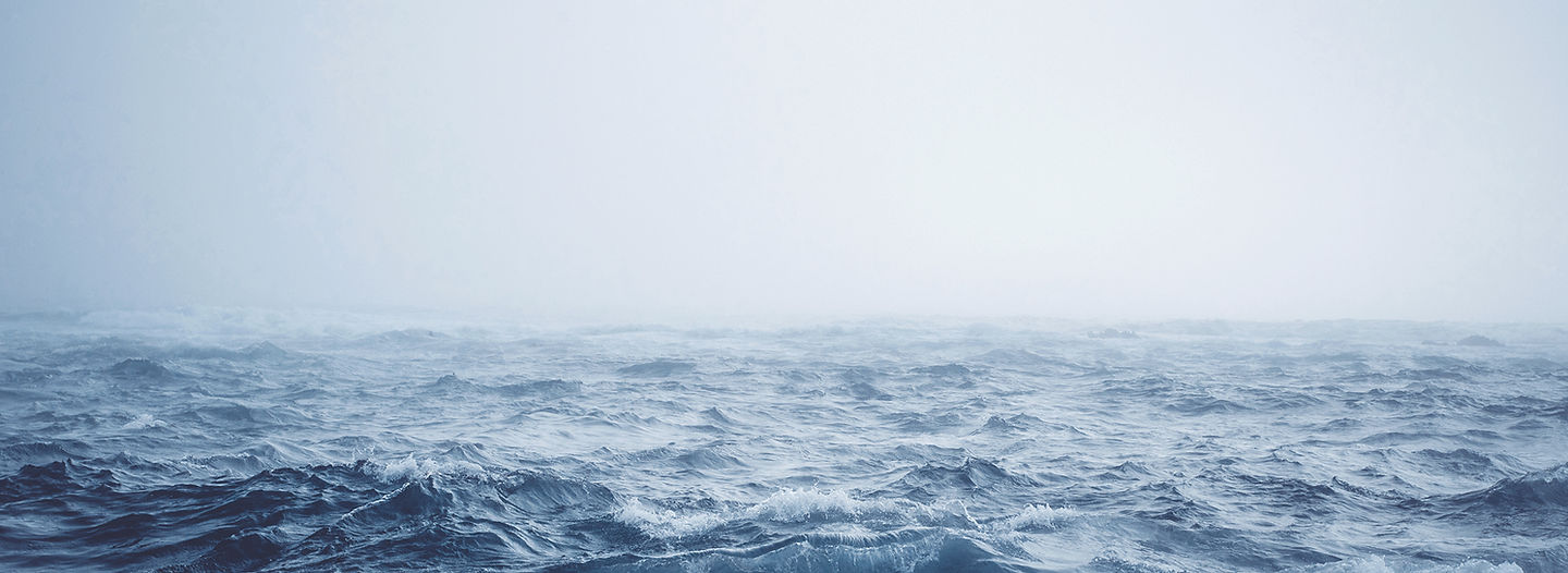 Rough grey open sea running to a hazy horizon