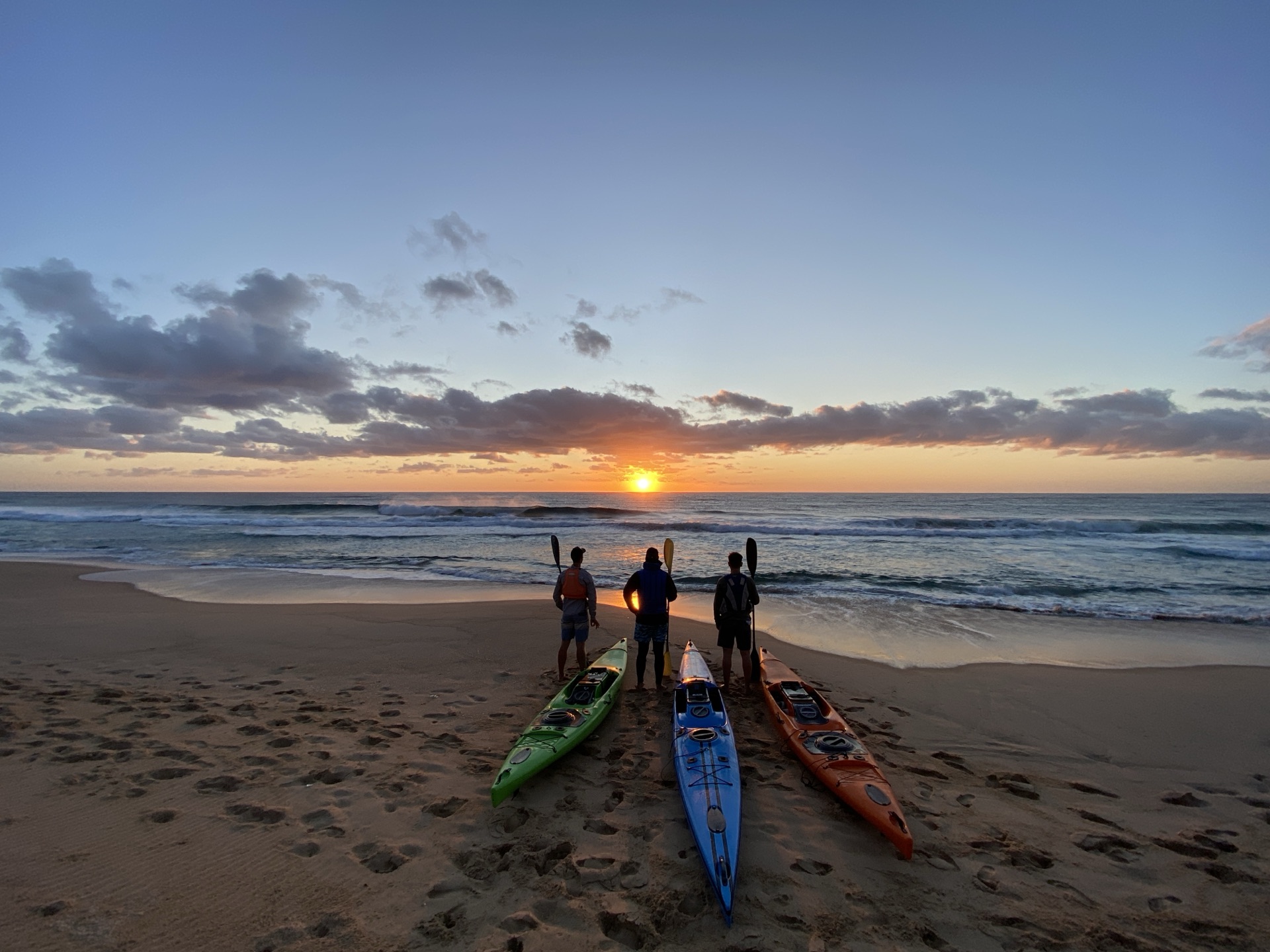 Kayaks lined up on the beach at sunrise
